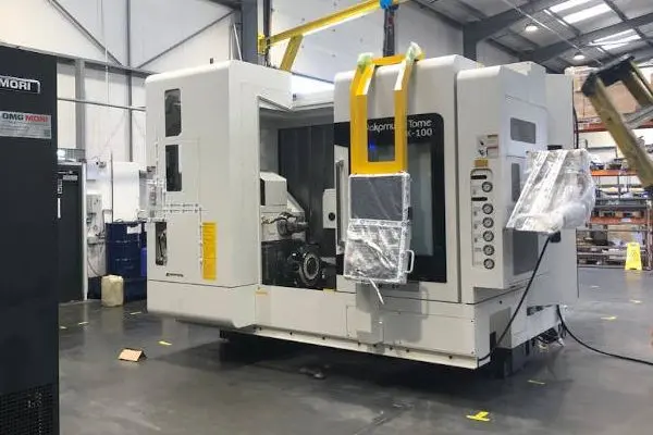 A large, white industrial CNC machine or press being prepared for transport.