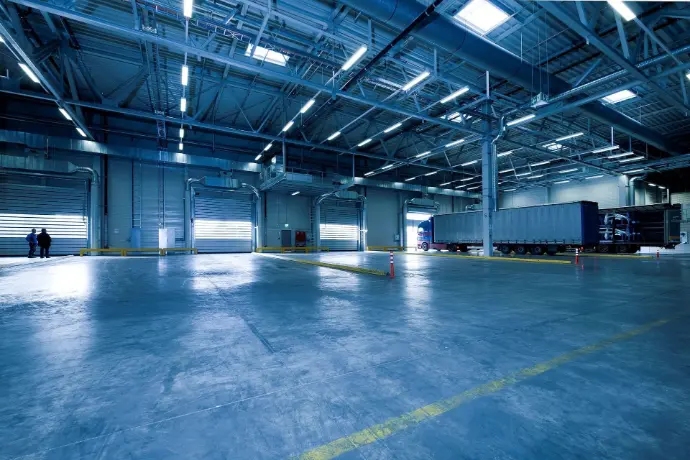 An interior perspective of a large, modern industrial space with high-gloss blue flooring and overhead lighting.
