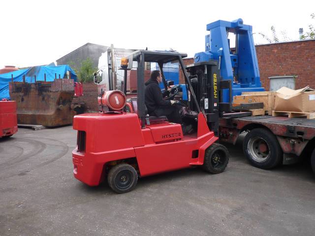 A red forklift truck parked in an outdoor industrial storage yard.